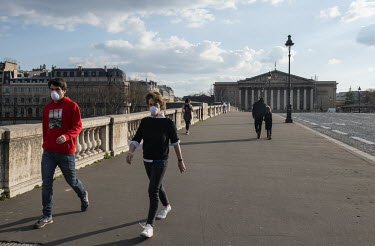 Pedestrians wearing face masks cross the Pont de la Concorde towards L'Assemblee Nationale. In response to the global spread of the novel COVID-19 virus, the French government has imposed severe measu...
