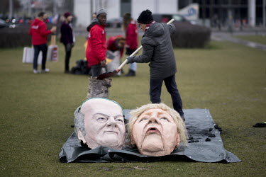 A pair of caricature model heads of German Federal Chancellor Angela Merkel and Federal Finance Minister and Vice-Chancellor Olaf Scholz at a demonstration, in front of the German Parliament Reichstag...