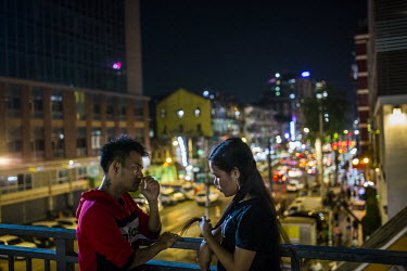 A couple on a date, stand on a pedestrian bridge in downtown Yangon.