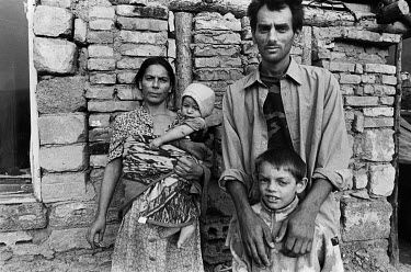 A Roma family stand in front of their house.