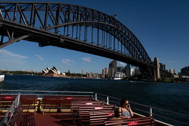A lone woman on the deck of a Sydney harbour ferry, as it passes near the Sydney Harbour Bridge. Ferries are quieter than usual as many office workers, tourists and locals are keeping away from public...