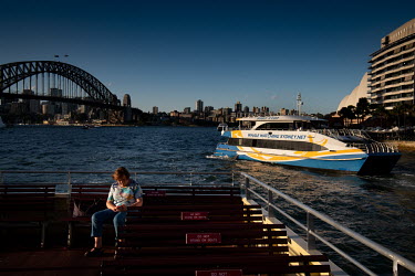 A lone woman on the deck of a Sydney harbour ferry, as it passes near the Sydney Harbour Bridge. Ferries are quieter than usual as many office workers, tourists and locals are keeping away from public...