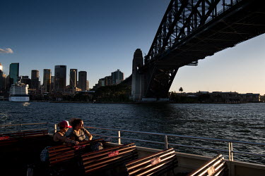 Women on the deck of a Sydney harbour ferry, as it passes near the Sydney Harbour Bridge. Ferries are quieter than usual as many office workers, tourists and locals are keeping away from public areas.