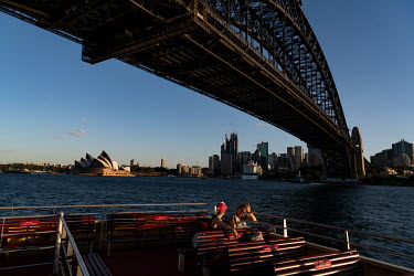 Women on the deck of a Sydney harbour ferry, as it passes near the Sydney Harbour Bridge. Ferries are quieter than usual as many office workers, tourists and locals are keeping away from public areas.
