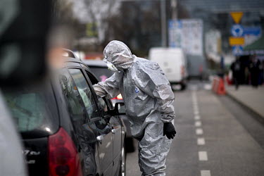 A Polish border and health patrol guard with a protective face mask and hazmat suit checks cars and passengers as coronavirus containment efforts are enforced on the Oder Bridge, the border crossing b...