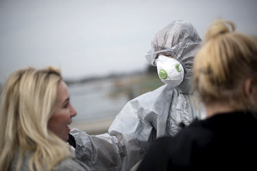 A Polish border and health patrol guard with a protective face mask and hazmat suit checks the body temperature of people crossing the border as coronavirus containment efforts are enforced on the Ode...