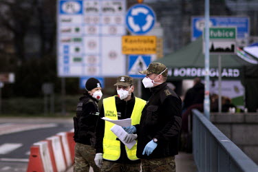 Polish border and health patrol guards, wearing face masks, check pedestrians and people crossing by car into Slubice as coronavirus containment efforts are enforced on the Oder Bridge, the crossing b...