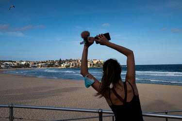 A woman looks out over a deserted Bondi Beach while exercising. Australian officials closed Sydney's iconic Bondi Beach on Saturday 21 March 2020, after thousands of people flocked there in recent day...
