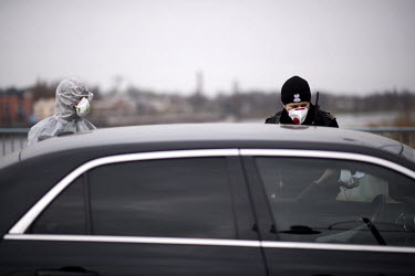 A Polish border and health patrol guard, with a protective face mask, questions a driver as coronavirus containment efforts are enforced on the Oder Bridge, the border crossing between Germany and Pol...