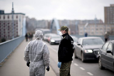 Polish border and health patrol guards, wearing protective face masks and a hazmat suit, as coronavirus containment efforts are enforced on the Oder Bridge, the border crossing between Germany and Pol...