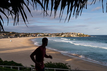 A man out jogging looks out over a deserted Bondi Beach. Australian officials closed Sydney's iconic Bondi Beach on Saturday 21 March 2020, after thousands of people flocked there in recent days, defy...