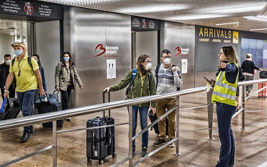 Travellers, many wearing face masks, are directed by airport staff as they enter the arrivals hall of Brussels Airport. They have been repatriated from various holiday destinations due to the coronavi...