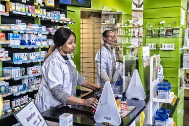A pharmacy where the staff are now working behind a plexiglass barriers to protect themselves against possible contamination with coronavirus.