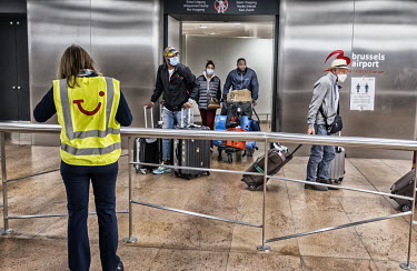 Travellers, many wearing face masks, enter the arrivals hall of Brussels Airport. They have been repatriated from various holiday destinations due to the coronavirus outbreak.