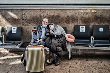 A couple rest on a bench at Brussels Airport where people are trying to find flights to return to their home countries. As more and more flights are cancelled, travelling by air has become increasingl...