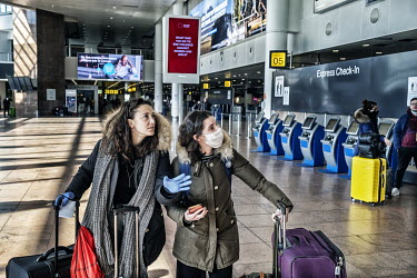 Two women looking at the check in points board at Brussels Airport where people are trying to find flights to return to their home countries. As more and more flights are cancelled, travelling by air...