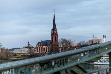 The 'Dreikönigskirche' seen from the 'Eiserner Steg' (Iron footbridge), a footbridge spanning the River Main, currently nearly deserted as people heed calls to restrict their movements during the cor...