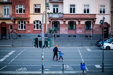 A man and his child on rollerskates crossing a street that is currently nearly deserted as people heed calls to restrict their movements during the coronavirus crisis.