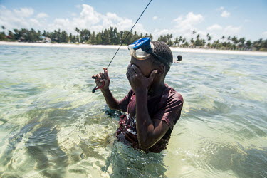 A boy wipes water from his eyes after diving for fish in the lagoon at Bwejuu.