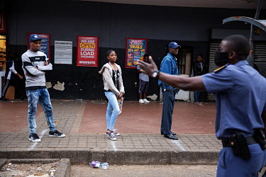 Police order shoppers queueing up outside a shop in Hillbrow to maintain a safe distance from each other.
