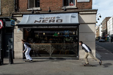 Two youths skateboard down an empty Old Compton Street in Soho, prior to the government's implementation of an enforceable lockdown.