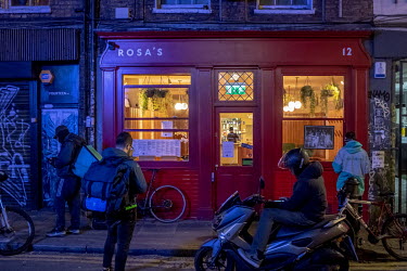 Delivery bicycle riders wait for orders outside a restaurant. With all restaurants closed for diners, delivery drivers are being kept busy. The following day, on the 25 March 2020, the Coronavirus Act...