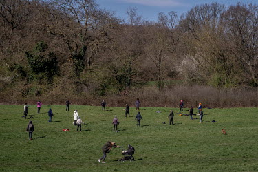 A woman pushes a pram past a 'group collective meditation practice' on Hampstead Heath. Although the group is observing social distancing, it was people ignoring the government's advice on social dist...