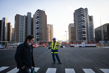 A security guard directs traffic in front of the accommodation towers in the Athlete's Village for the Tokyo 2020 Olympic and Paralympic Games.