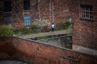 A man jogging past old factories and mills in the Ancoats district seen from AWOL studios.