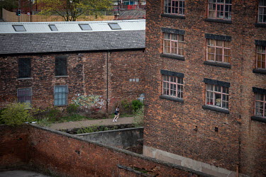 Two women jogging past old factories and mills in the Ancoats district seen from AWOL studios.