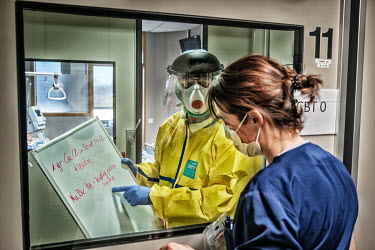 Medical staff working in an intensive care isolation ward at the Jessa hospital communicate with hand written notes with a nurse outside the room.