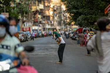 A girl plays cricket in a face mask on a deserted street during the 21 day coronavirus lockdown.
