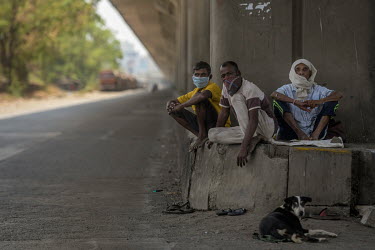 Migrant workers, wearing face masks or scarves, rest below the eastern freeway. Migrant workers have become stuck in Mumbai, without work or often shelter, as the borders of all the districts in India...