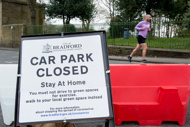 A jogger runs past a sign and barriers barring entry to a car park outside Roberts Park in Saltaire, a popular tourist destination. As part of the UK's social distancing and coronavirus lockdown measu...