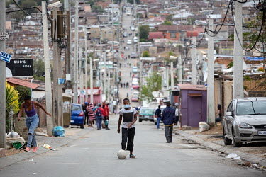 A boy plays football on a street in Alexandra Township. Although supposedly under a lockdown due to the coronavirus epidemic, there are some circumstances under which people are allowed outside, altho...