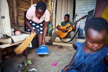 Patric (centre) plays his 12 sting guitar outside his shack in the Diepsloot township while his wife Shyine cleans up and his child Phethokuhle plays during the coronavirus lockdown.