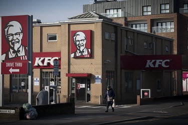 A woman wearing an improvised face mask passes a drive-through KFC, closed due to the coronavirus lockdown.