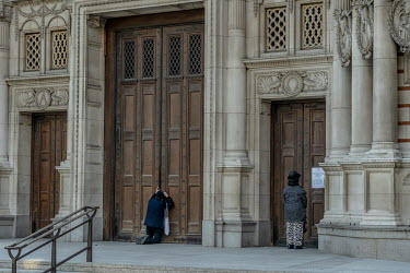 A woman kneels to pray at the doors of Westminster Cathedral in central London on Good Friday. This year all churches are closed to the public due to the coronavirus lockdown.