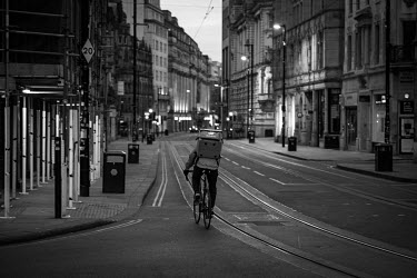 A Deliveroo cyclist on a near empty Cross Street in Manchester's city centre on a Saturday evening during the coronavirus lockdown.