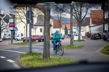 A woman is cycling with a helmet and a face mask.