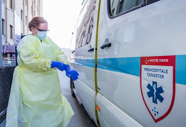 A paramedic puts on personal protective equipment (PPE) as she prepares to move patients by ambulance at Drammen hospital.