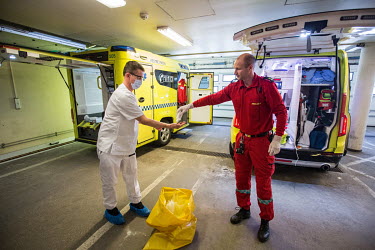 A paramedic is helped to sanitise his hands by a colleague after moving patients by ambulance at Drammen hospital.