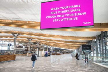 A huge digital sign at an almost deserted Gardermoen Airport displays an information message about coronavirus sanitation and social distancing.  Restrictions on public gatherings and travel have grou...