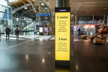 A sign at Gardermoen Airport, written in Norwegian and English, asking people to observe social distancing rules.   Restrictions on public gatherings and travel have grounded most aeroplanes, and stop...