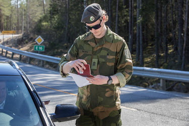 Krisitan Moen checking papers of travellers at a checkpoint on a road leading to the closed border with Sweden.
