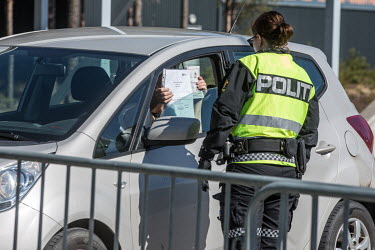A woman showing her travel permits to a police officer at the closed border crossing point with Sweden.