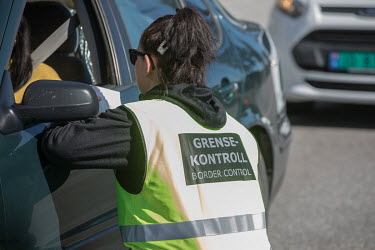 A border control officer talks with a car driver at the closed border crossing point with Sweden.