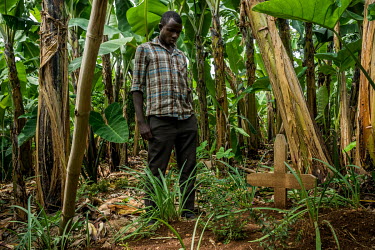 A young man meditates beside the grave of his father, Clemence Klofas, in the banana plantation adjoining the family home. A few months ago, his father was discovered by his daughhters, hanging from a...