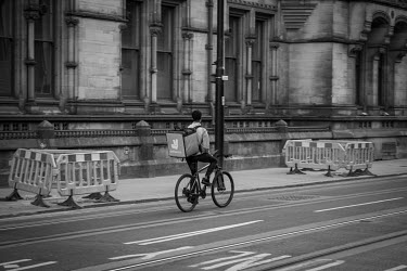 A Deliveroo cyclist rides past Manchester Town Hall delivering take-aways in an almost empty Manchester city centre on a Saturday evening during the coronavirus lockdown.