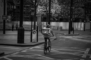 A Deliveroo delivery cyclist delivering take-aways in an almost empty Manchester city centre on a Saturday evening during the coronavirus lockdown.